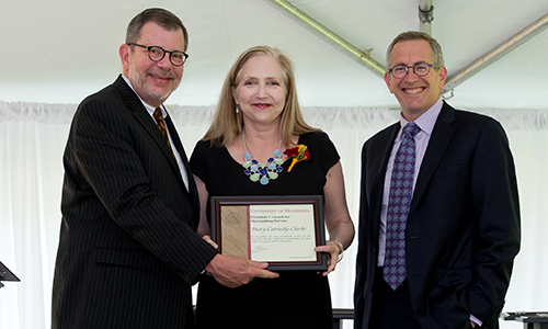 Mary Cannedy-Clarke poses with President Eric Kaler and Professor William Tolman, chair of the President's Award for Outstanding Service Committee. Cannedy-Clarke is holding his certificate.
