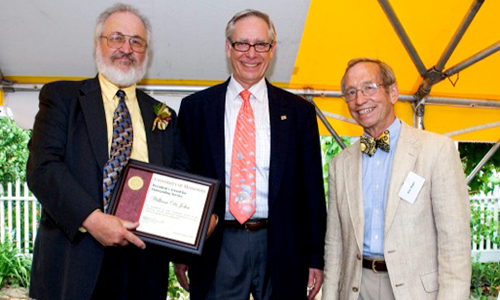 William DeJohn poses with President Robert H. Bruininks and Professor Pete Magee. DeJohn is holding his award certificate. 