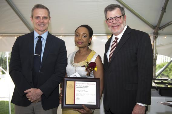 Etty DeVeaux poses with President Eric Kaler and Professor Robert Geraghty, chair of the President's Award for Outstanding Service Committee. DeVeaux is holding her certificate.