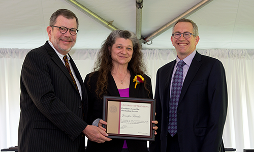 Jennifer Franko poses with President Eric Kaler and Professor William Tolman, chair of the President's Award for Outstanding Service Committee. Franko is holding her certificate.