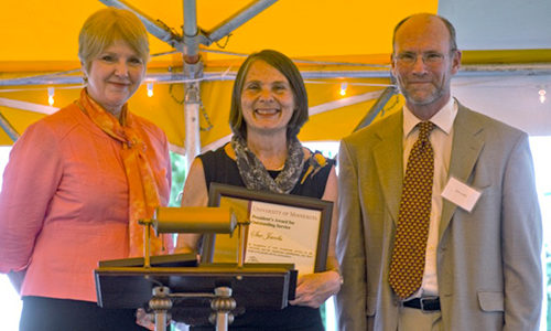 Sue Jacobs poses with Executive Vice President and Provost Karen Hanson and Professor James Luby, chair of the President's Award for Outstanding Service Committee. Jacobs is holding her certificate.