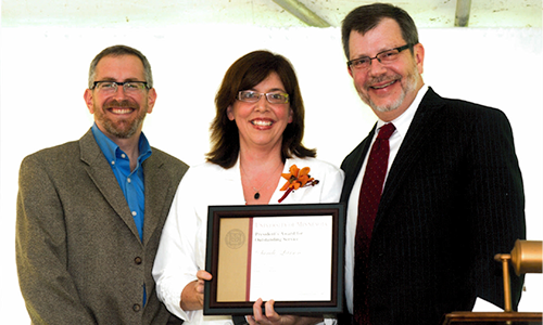 Sandi Larson poses with President Eric Kaler and Professor William Tolman, chair of the President's Award for Outstanding Service Committee. Larson is holding her certificate.