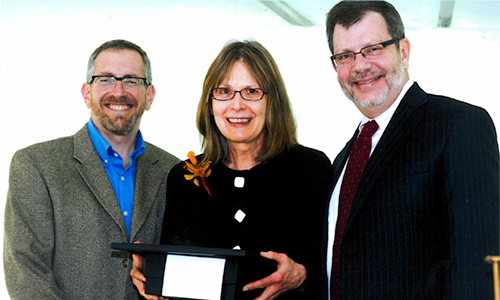 Linda DeBeau-Melting poses with President Eric Kaler and Professor William Tolman, chair of the President's Award for Outstanding Service Committee. DeBeau-Melting is holding her certificate.