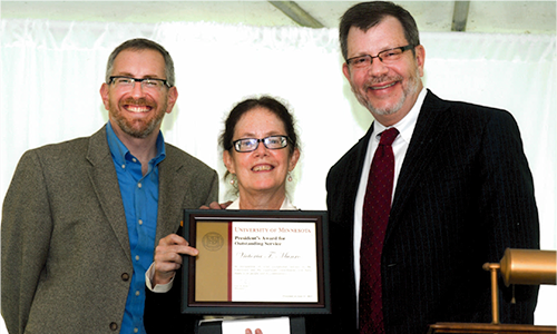 Victoria T. Munro poses with President Eric Kaler and Professor William Tolman, chair of the President's Award for Outstanding Service Committee. Munro is holding her certificate.