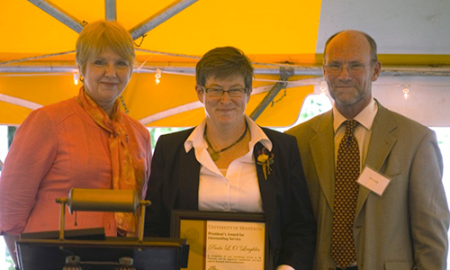 Paula L. O'Loughlin poses with Executive Vice President and Provost Karen Hanson and Professor James Luby, chair of the President's Award for Outstanding Service Committee. O'Loughlin is holding her certificate.