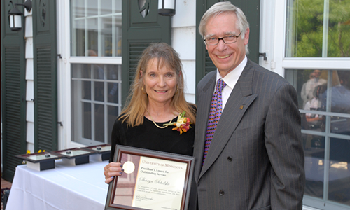 Sharyn Schelske poses with President Robert H. Bruininks. Shelske is holding her award certificate.