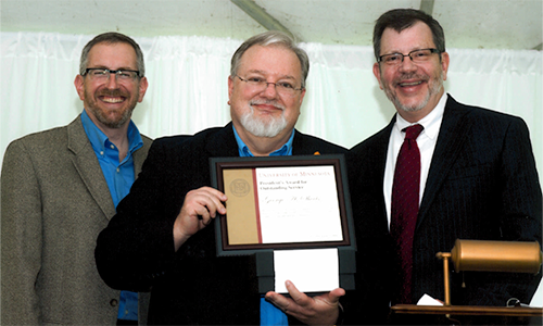 George A. Sheets poses with President Eric Kaler and Professor William Tolman, chair of the President's Award for Outstanding Service Committee. Sheets is holding his certificate.