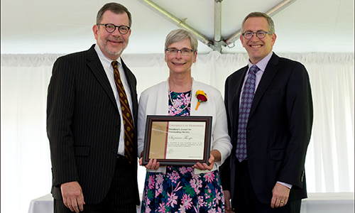 Suzanne Thorpe poses with President Eric Kaler and Professor William Tolman, chair of the President's Award for Outstanding Service Committee. Thorpe is holding her certificate.
