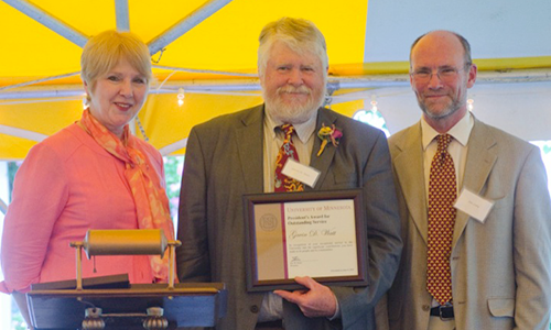 Gavin D. Watt poses with Executive Vice President and Provost Karen Hanson and Professor Jame Luby, chair of the President's Award for Outstanding Service Committee. Watt is holding his certificate.