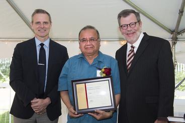Luis Ramos-Garcia poses with President Eric Kaler and Professor Robert Geraghty, chair of the President's Award for Outstanding Service Committee. Ramos-Garcia is holding his certificate.