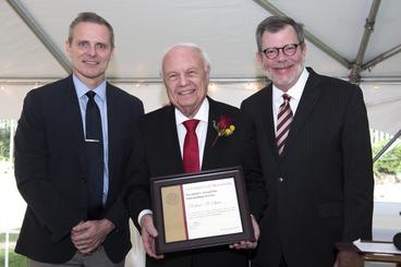 Robert A. Stein poses with President Eric Kaler and Professor Robert Geraghty, chair of the President's Award for Outstanding Service Committee. Stein is holding his certificate.