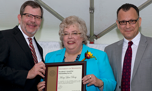 Mary Lisa (Lisa) Berg poses with President Eric Kaler and Professor Fotis Sotiropoulos, representing the President's Award for Outstanding Service Committee. Berg is holding her certificate.