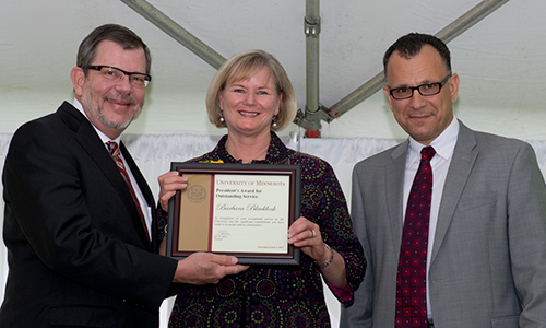 Barbara Blacklock poses with President Eric Kaler and Professor Fotis Sotiropoulos, representing the President's Award for Outstanding Service Committee. Blacklock is holding her certificate.