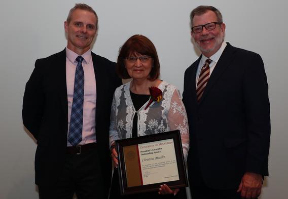 Recipient Christine Mueller receiving her award pictured with President Eric W. Kaler and Robert Geraghty, chair, President's Award committee.