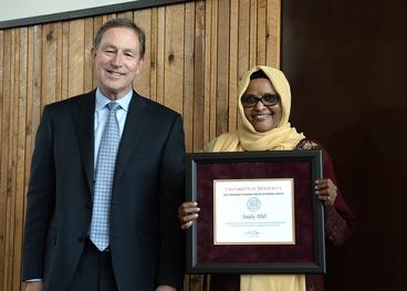 Interim President Jeff Ettinger and Saida Abdi holding framed citation